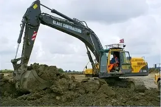 A Clark Contracting excavator digging spoil, with its operator in the cab