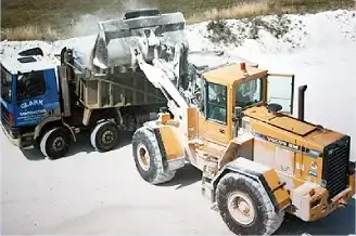 A yellow loading shovel filling a blue Clark tipper lorry in a quarry