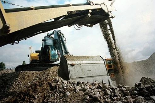 An excavator feeding a screener as crushed material pours off its conveyor